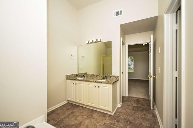 bathroom featuring double vanity, baseboards, visible vents, and a shower