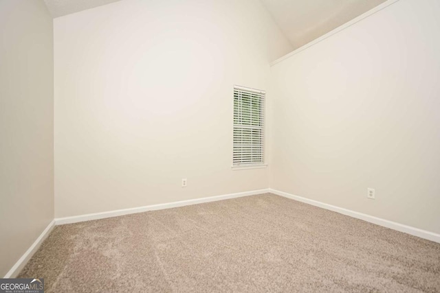 carpeted empty room with baseboards and lofted ceiling