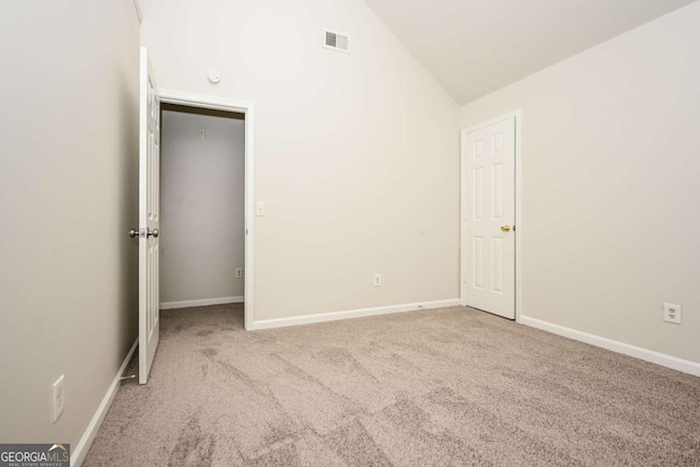 unfurnished bedroom with carpet floors, baseboards, lofted ceiling, and visible vents