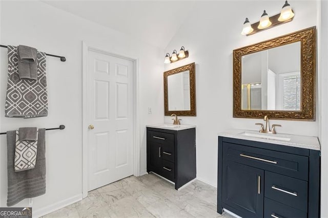 bathroom with a sink, vaulted ceiling, marble finish floor, and two vanities