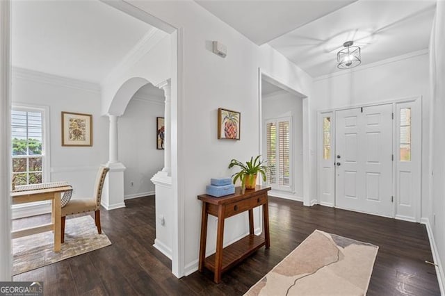 entryway featuring decorative columns, crown molding, arched walkways, wood finished floors, and baseboards