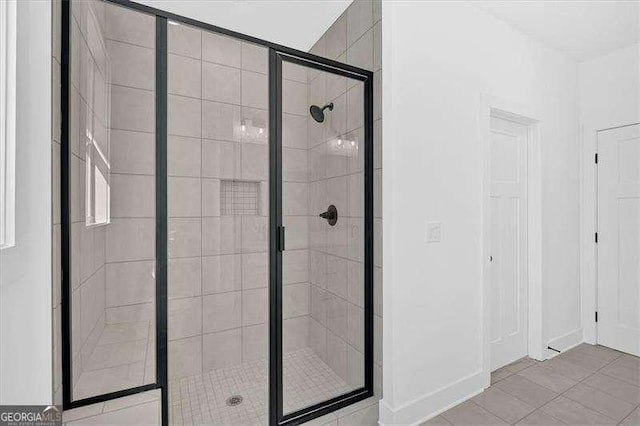 bathroom featuring baseboards, tile patterned floors, and a stall shower