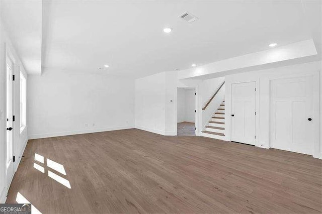 interior space featuring recessed lighting, baseboards, wood finished floors, visible vents, and stairway