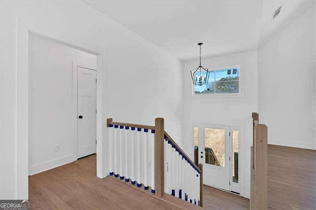 staircase with baseboards, an inviting chandelier, wood finished floors, and visible vents