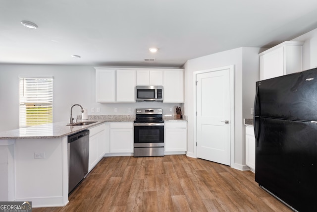 1341 Midnight Ride Ct, Hampton, GA 30228 - kitchen featuring a sink, light wood-style flooring, appliances with stainless steel finishes, and a peninsula