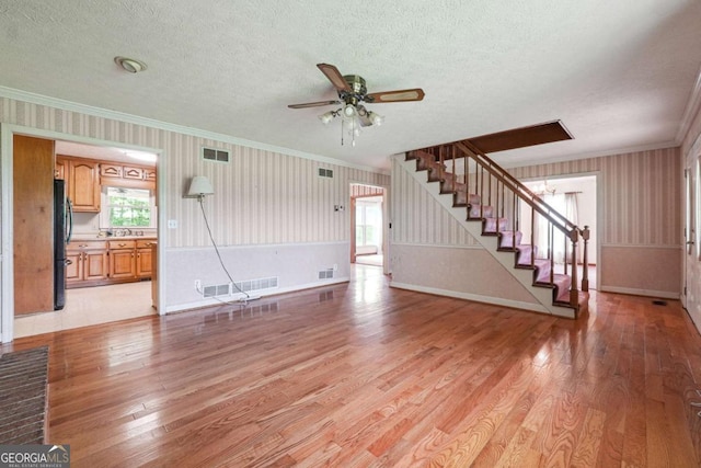 6545 Westbrook Rd, Gainesville, GA 30506 - unfurnished living room with crown molding, light wood finished floors, wallpapered walls, visible vents, and stairway