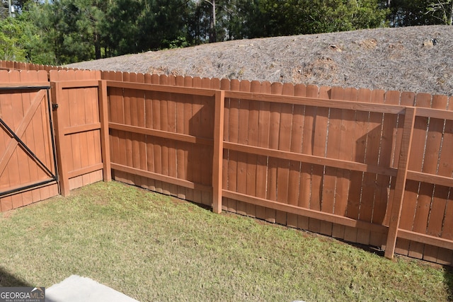 view of gate with a lawn and a fenced backyard