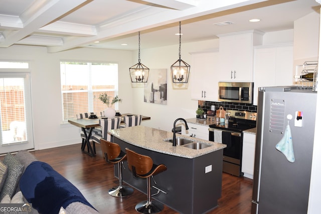 kitchen featuring a breakfast bar area, stainless steel appliances, dark wood-style floors, and a sink