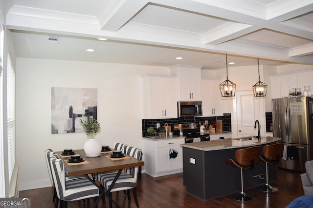 kitchen with decorative backsplash, a kitchen breakfast bar, a sink, light stone counters, and stainless steel appliances