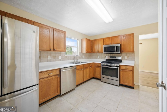 kitchen with stainless steel appliances, a sink, tasteful backsplash, light countertops, and a textured ceiling
