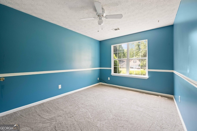 carpeted empty room with a ceiling fan, baseboards, and a textured ceiling