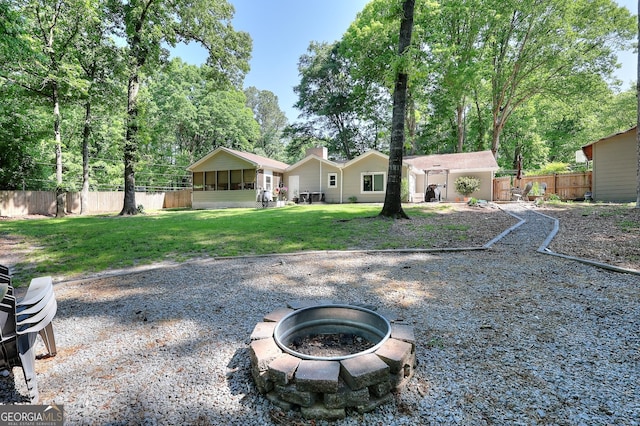 rear view of house with fence, a chimney, a lawn, and a fire pit