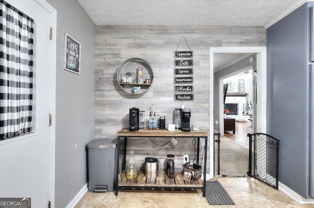 bar featuring wood walls, ornamental molding, an accent wall, baseboards, and a textured ceiling
