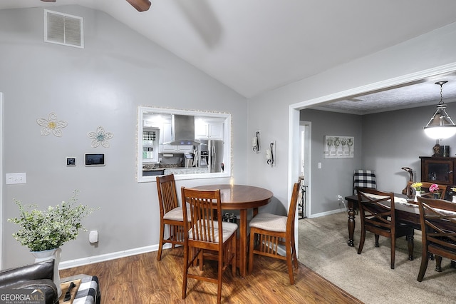 dining area featuring ceiling fan, baseboards, wood finished floors, lofted ceiling, and visible vents