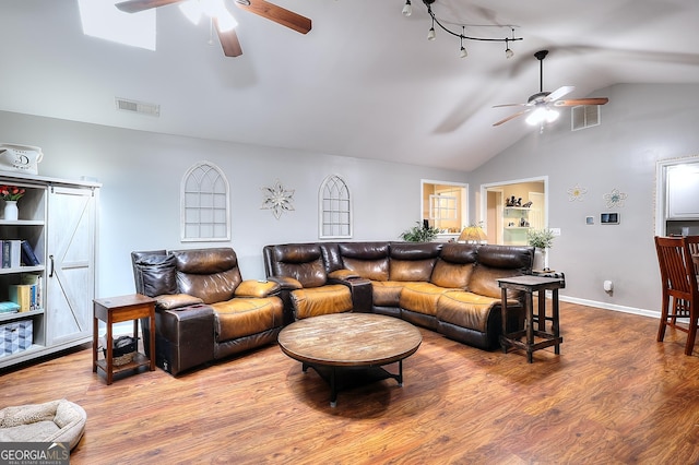 living area featuring wood finished floors, a ceiling fan, a barn door, and visible vents