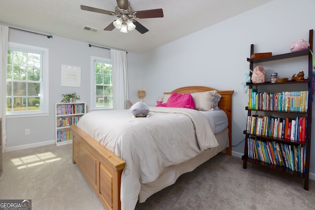 bedroom with baseboards, visible vents, a textured ceiling, and light colored carpet