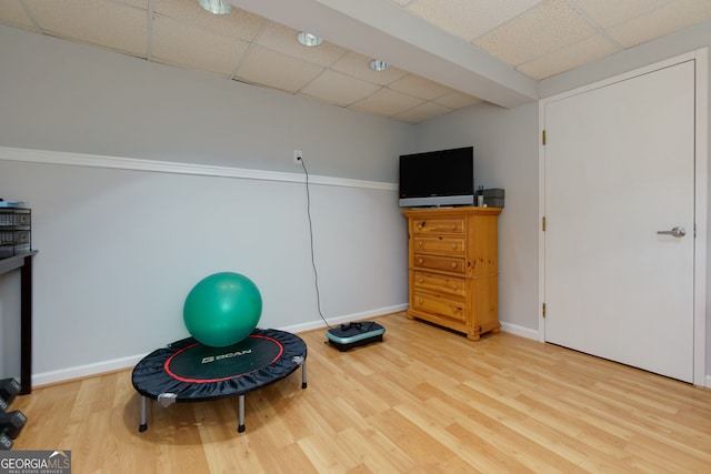 workout area featuring baseboards, a drop ceiling, and wood finished floors