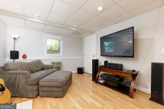 living room featuring baseboards, a drop ceiling, and light wood-style flooring