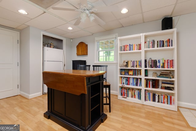 office space featuring light wood-style floors, ceiling fan, and a drop ceiling