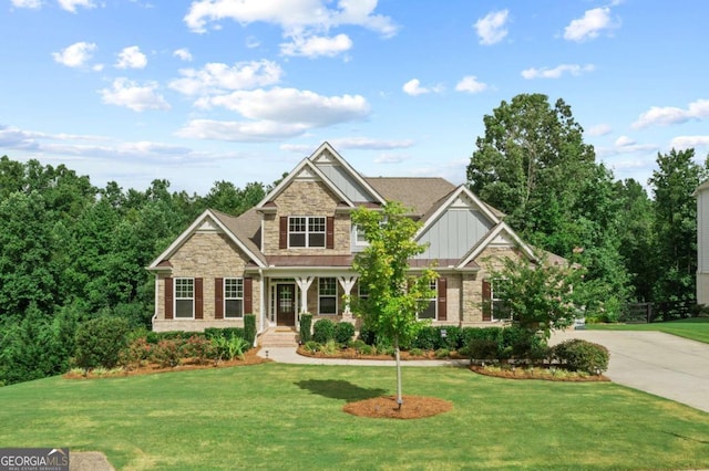 craftsman-style house featuring board and batten siding, a front yard, stone siding, and concrete driveway