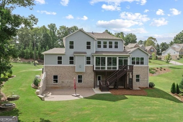 rear view of property featuring stairs, brick siding, a sunroom, a lawn, and a patio