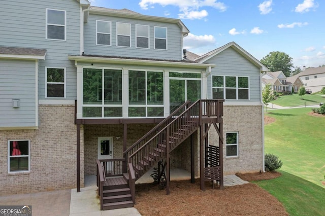 rear view of house with brick siding, a sunroom, stairway, a patio, and a yard