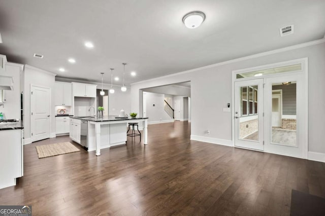 kitchen featuring dark countertops, a sink, stainless steel dishwasher, visible vents, and ornamental molding