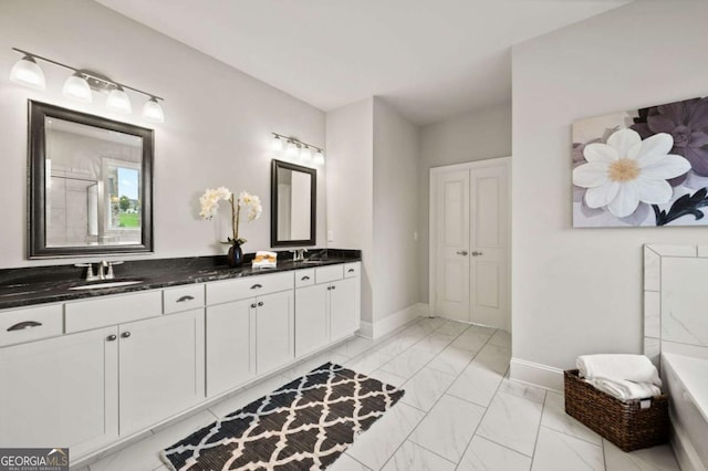 full bath with baseboards, a sink, marble finish floor, and a bathing tub