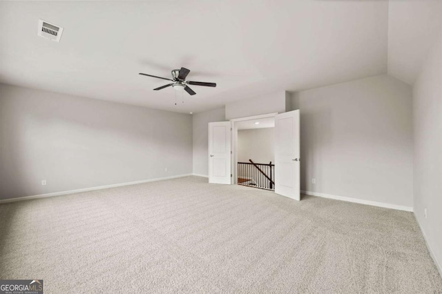 carpeted spare room with ceiling fan, visible vents, and baseboards