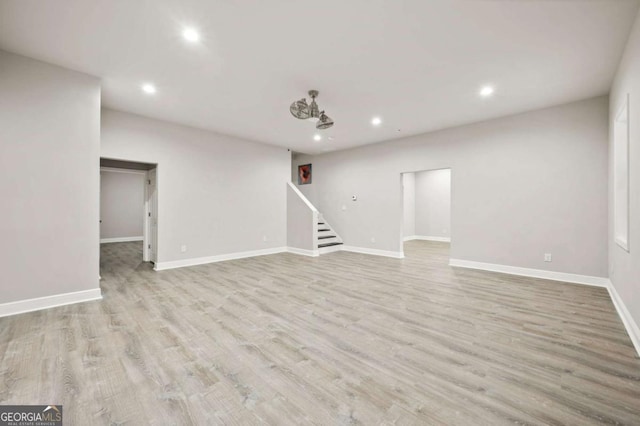 finished below grade area featuring baseboards, recessed lighting, wood finished floors, and stairs