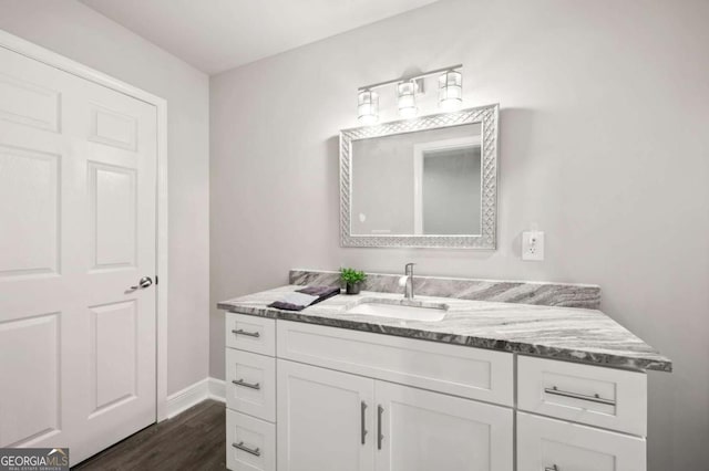 bathroom with baseboards, wood finished floors, and vanity