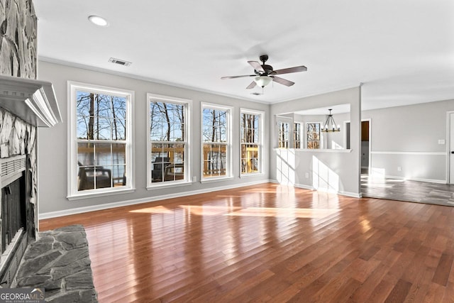 unfurnished living room featuring baseboards, a fireplace, ceiling fan with notable chandelier, and visible vents
