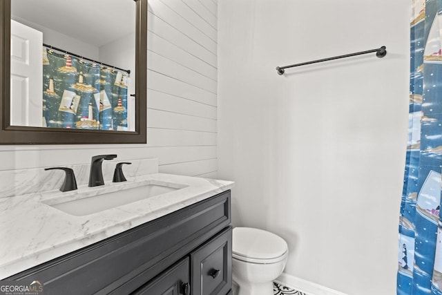 bathroom with vanity, wood walls, toilet, and a shower with curtain