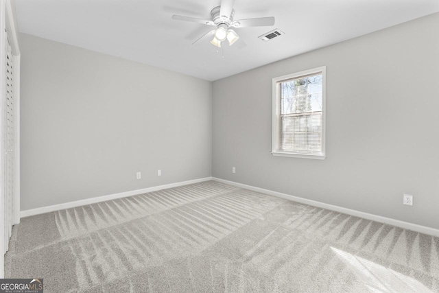 carpeted empty room featuring baseboards, ceiling fan, and visible vents