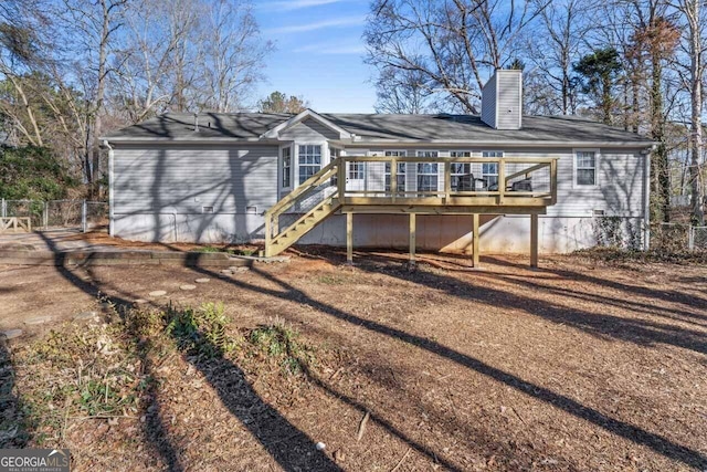 rear view of house featuring a deck, fence, a chimney, and stairs