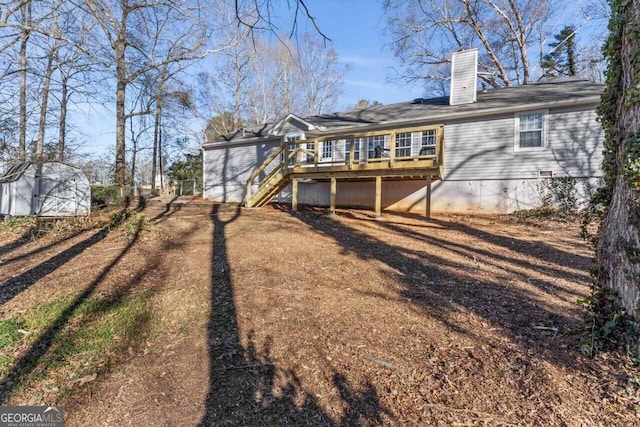 back of property with a deck, a chimney, and stairway