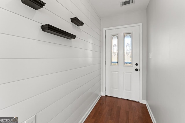 doorway featuring wooden walls, baseboards, visible vents, and dark wood finished floors