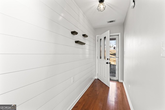 doorway with baseboards, dark wood-style floors, and visible vents