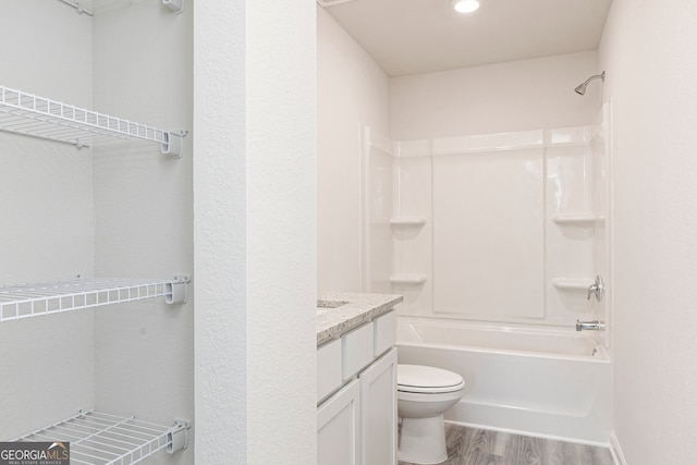 bathroom with toilet, washtub / shower combination, wood finished floors, and vanity