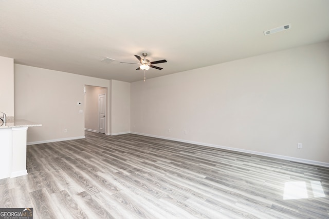 unfurnished living room featuring baseboards, light wood finished floors, ceiling fan, and visible vents
