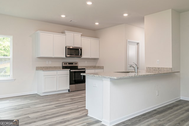 kitchen with white cabinets, appliances with stainless steel finishes, a sink, and light wood-type flooring
