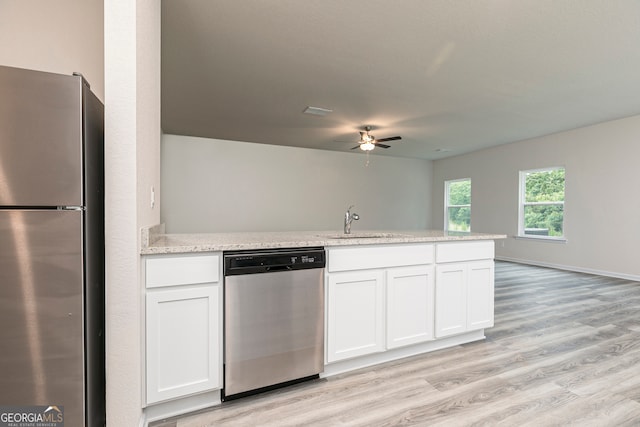 kitchen featuring light wood-style floors, ceiling fan, white cabinets, a sink, and appliances with stainless steel finishes