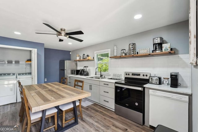 kitchen with washing machine and clothes dryer, appliances with stainless steel finishes, open shelves, a sink, and light countertops