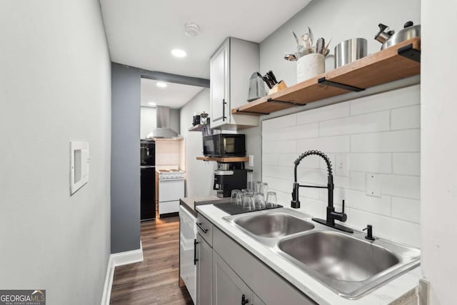 kitchen with tasteful backsplash, open shelves, a sink, white appliances, and wall chimney exhaust hood