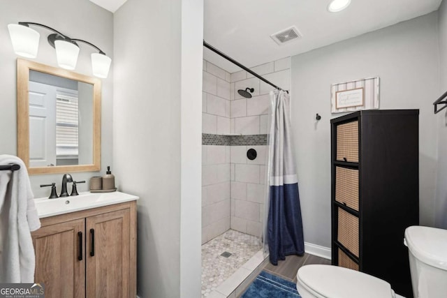 bathroom with vanity, a tile shower, toilet, and visible vents