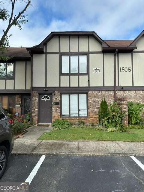 view of front of home featuring stucco siding, uncovered parking, and brick siding
