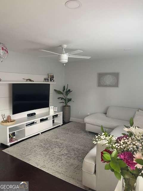 living area with baseboards and ceiling fan