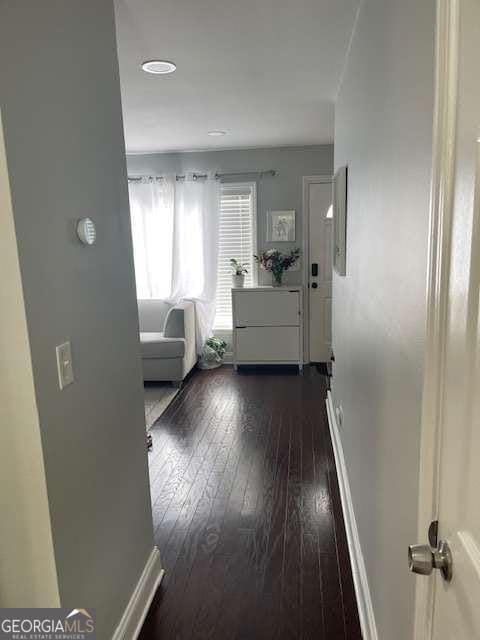 corridor featuring baseboards and dark wood finished floors