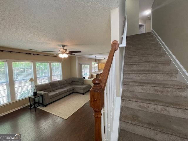 staircase with baseboards, a textured ceiling, ceiling fan, and wood finished floors