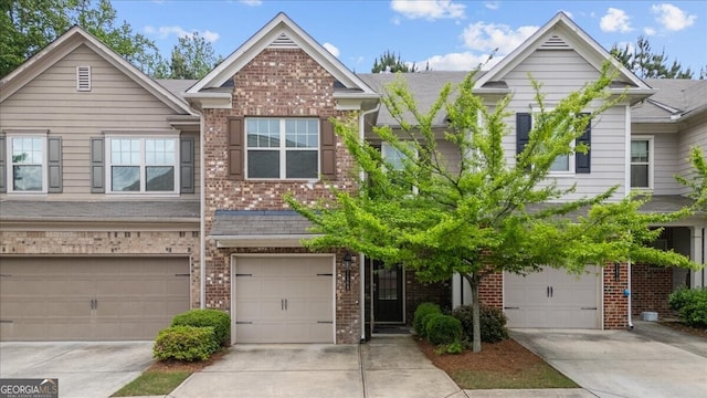 townhome / multi-family property with concrete driveway, brick siding, and an attached garage